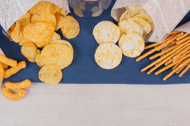 Photo gratuite chips, craquelins et bretzels sur nappe bleue.