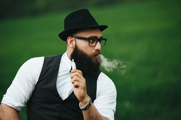 Photo gratuite close-up de l'homme avec un chapeau de fumer un cigare électronique