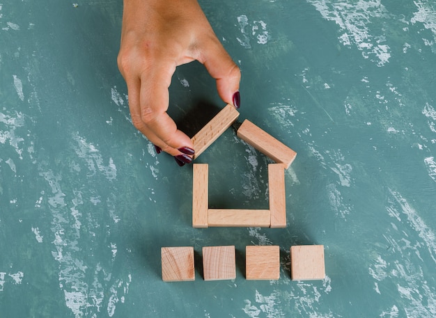 Photo gratuite concept immobilier avec des blocs de bois à plat. femme faisant modèle de maison.