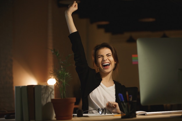 Photo gratuite concepteur de jeune femme bâillement assis dans le bureau la nuit