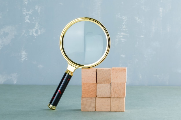 Photo gratuite conceptuel de recherche avec des blocs de bois, vue de côté de la loupe.