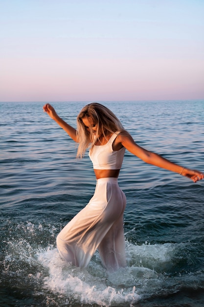 Photo gratuite coucher de soleil femme en haut blanc et pantalon mouillé. tenue bohème.