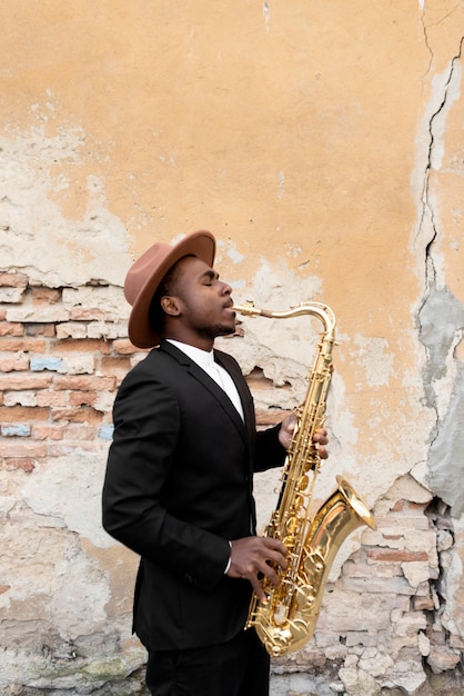 Photo gratuite coup moyen homme avec costume jouant du saxophone