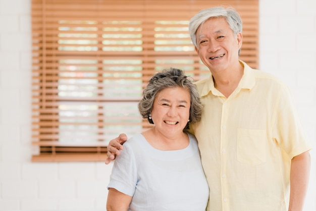 Photo gratuite couple de personnes âgées asiatiques se sentir heureux en souriant et en regardant vers la caméra tout en se détendre dans le salon à la maison.