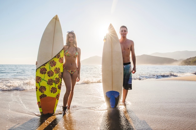 Photo gratuit couple de surfeurs avec leurs planches de surf