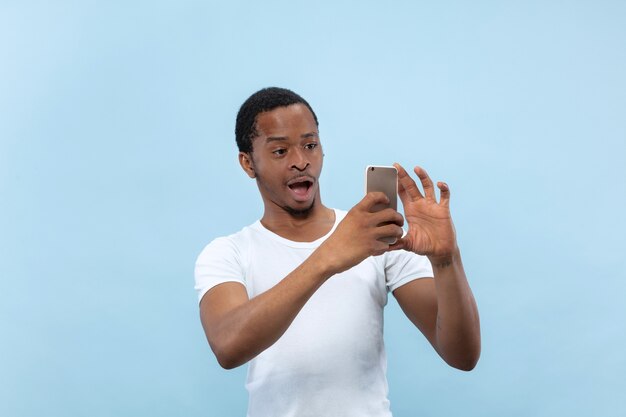 Demi-longueur gros plan portrait de jeune homme afro-américain en chemise blanche sur l'espace bleu