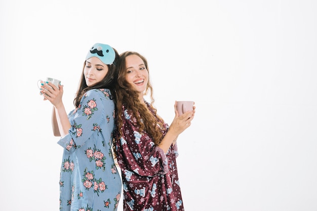 Photo gratuite deux amies debout dos à dos tenant une tasse de café