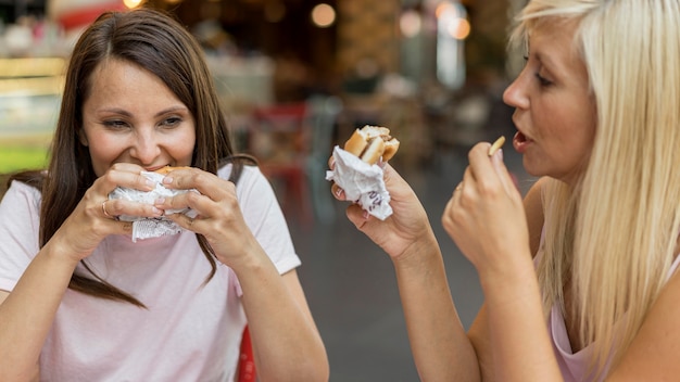 Deux amies de manger des hamburgers avec des frites au restaurant