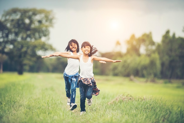 Photo gratuit deux petites filles mignonnes courent sur l&#39;herbe verte. meilleurs amis.