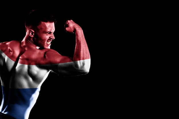 Photo gratuite drapeau néerlandais sur fond noir beau jeune homme musclé