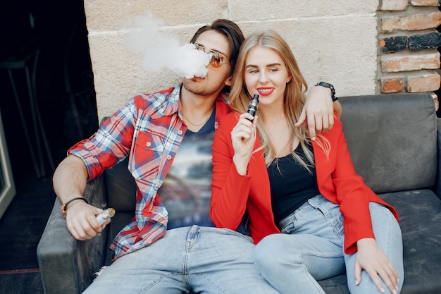 Photo gratuite Élégant jeune couple avec vape dans un café