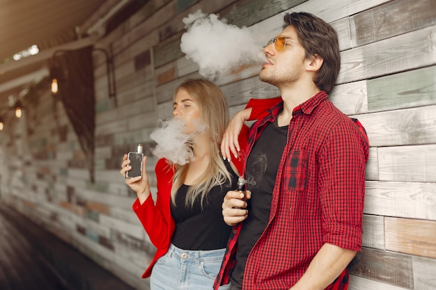 Photo gratuite Élégant jeune couple avec vape dans une ville