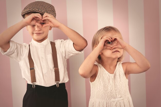 Photo gratuite enfants regardant à travers la forme de coeur des mains