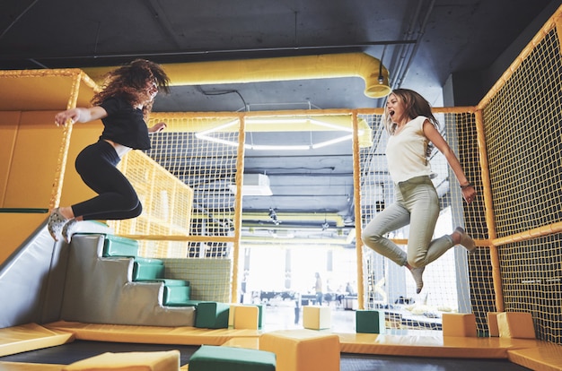 Photo gratuite l'entreprise est une jeune femme qui s'amuse avec des blocs souples sur une aire de jeux pour enfants dans un centre de trampoline.