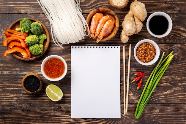 Photo gratuite Épices et baguettes plates de nouilles avec cahier vierge