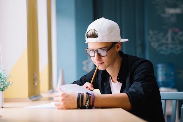 Photo gratuite Étudiant pensif travaillant dans les devoirs