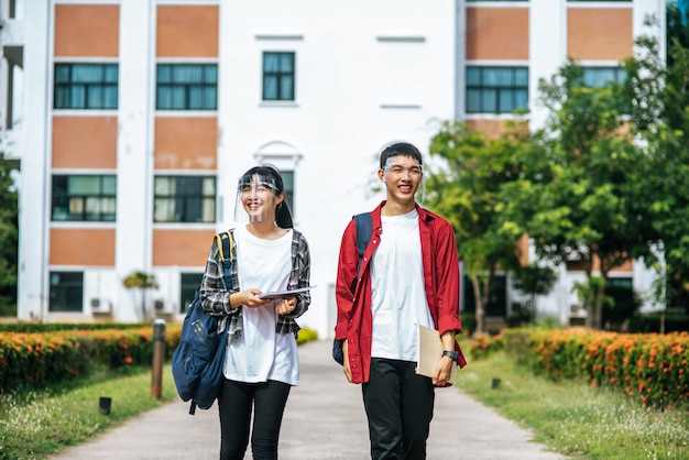 Photo gratuite les étudiants masculins et féminins portent un visage chill et se tiennent devant l'université.