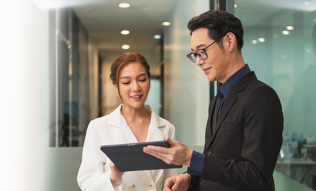 Photo gratuite femme d'affaires asiatique souriante montrant une tablette à son manager lors d'une réunion au bureau