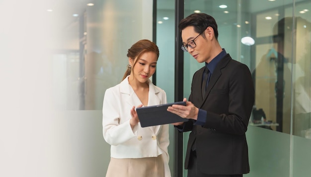 Photo gratuite femme d'affaires asiatique souriante montrant une tablette à son manager lors d'une réunion au bureau