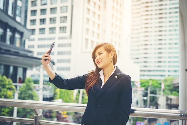 Photo gratuite femme d'affaires prenant selfie sur le téléphone devant le bâtiment de bureau.