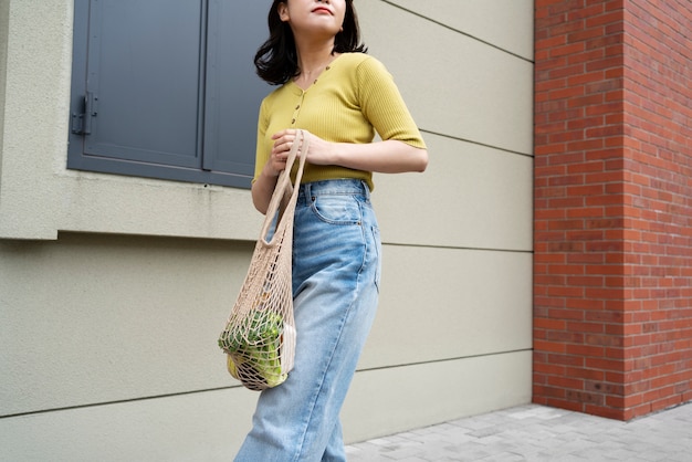 Photo gratuite femme à angle bas portant des provisions dans un sac fourre-tout