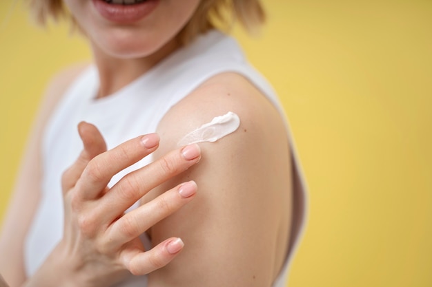 Photo gratuite femme appliquant une lotion sur l'épaule