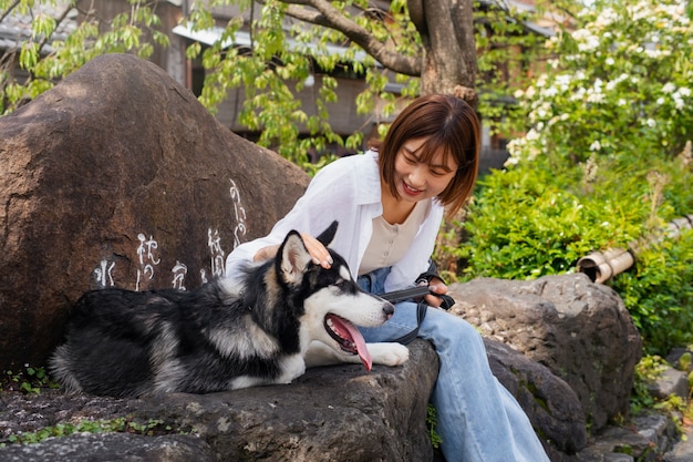 Photo gratuit femme asiatique promenant son chien husky à l'extérieur