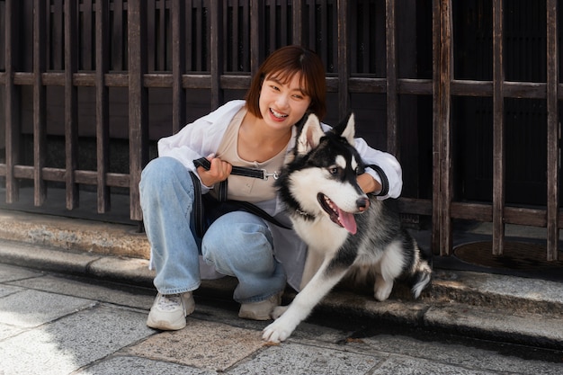 Photo gratuit femme asiatique promenant son chien husky à l'extérieur