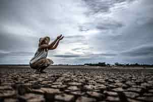 Photo gratuite une femme assise demande de la pluie pendant la saison sèche et le réchauffement climatique