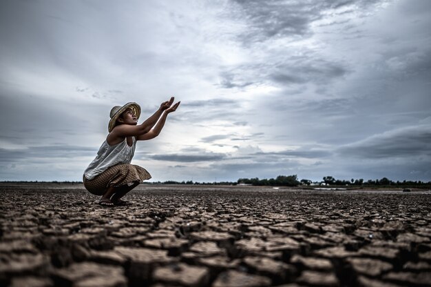 Une femme assise demande de la pluie pendant la saison sèche et le réchauffement climatique