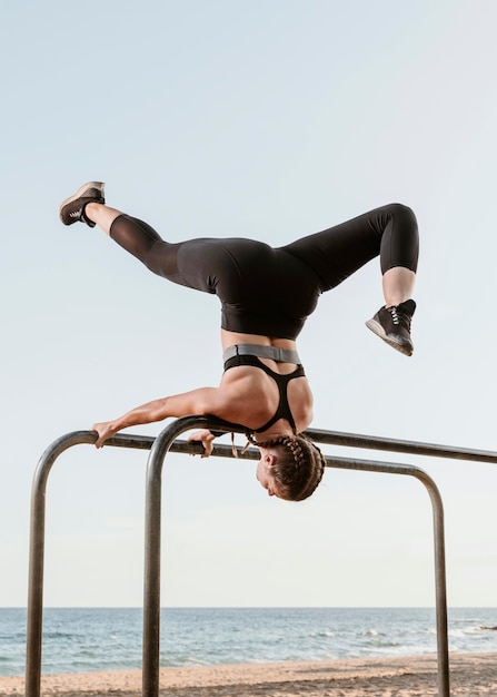 Photo gratuite femme athlétique faisant des exercices de remise en forme à l'extérieur au bord de la plage