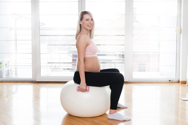 Femme enceinte sur la balle de gymnastique