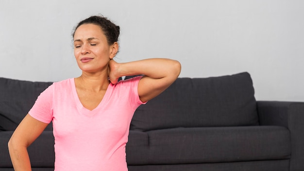 Photo gratuite femme enceinte à la maison tenant son cou pendant l'exercice