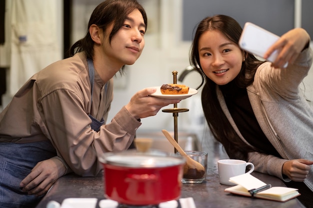 Photo gratuite femme japonaise prenant le selfie avec l'homme et le beignet dans un restaurant