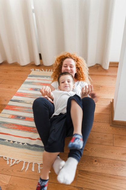 Photo gratuite femme jouant avec son enfant sur un plancher de bois franc