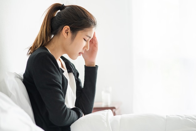 La femme malade avait mal à la tête et les mains touchaient sa tête sur le lit.