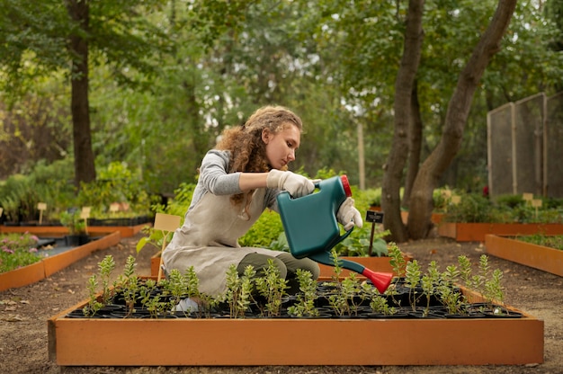 Photo gratuite femme plein coup arrosant les plantes du jardin