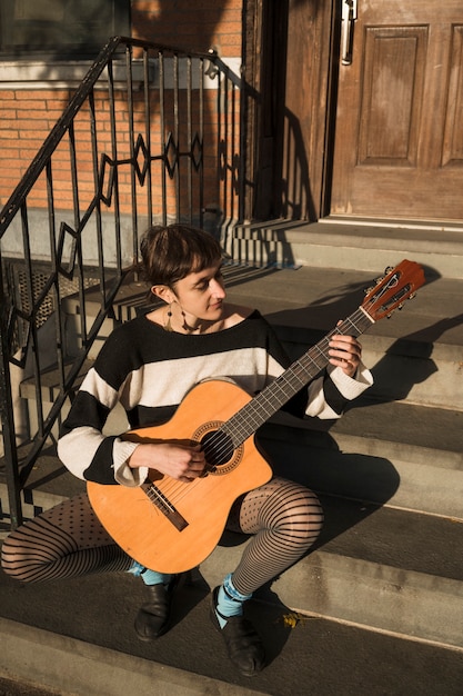 Photo gratuit femme pleine de coups jouant de la guitare à l'extérieur