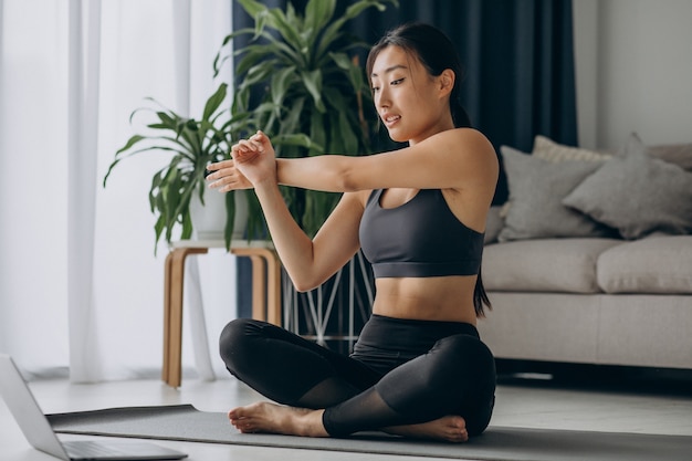 Photo gratuit femme qui s'étend sur un tapis de yoga à la maison