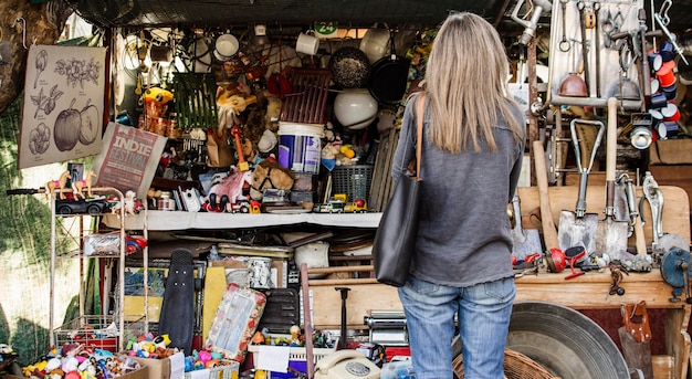 Photo gratuit femme à la recherche de quelque chose à acheter dans un marché d'antiquités