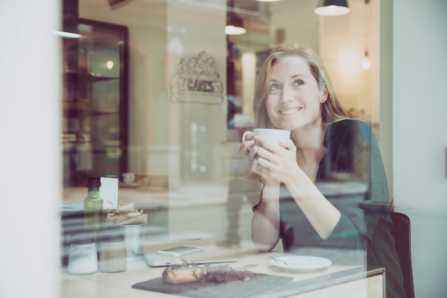 Photo gratuite femme souriante bénéficiant d'une boisson chaude au café