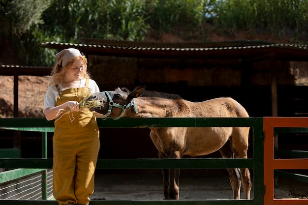 Photo gratuite femme souriante de tir moyen nourrissant le cheval