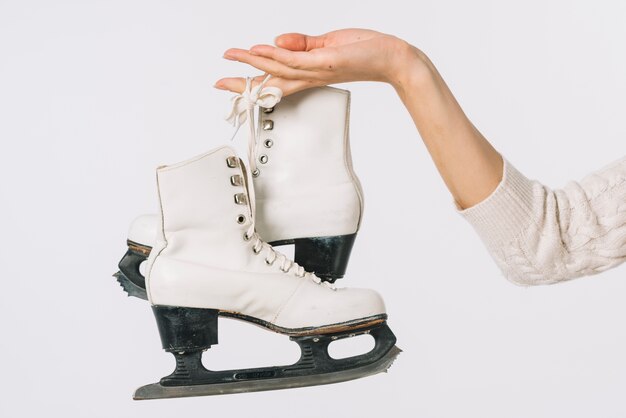 Femme tenant des patins blancs à la main