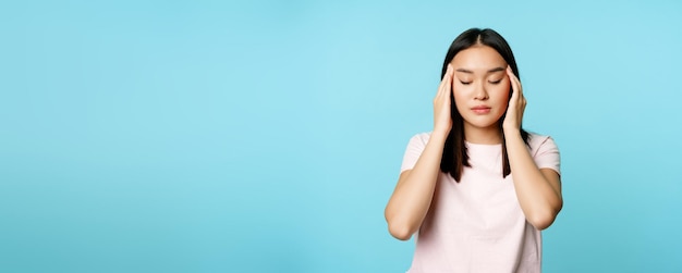 Photo gratuite fille asiatique frottant la tête de massage avec les doigts et fermer les yeux massage de maux de tête ayant la migraine