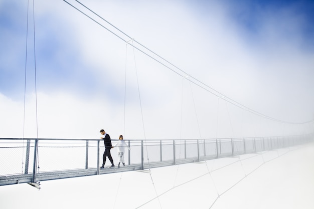 Photo gratuit fille et garçon marchant sur le pont dans les nuages