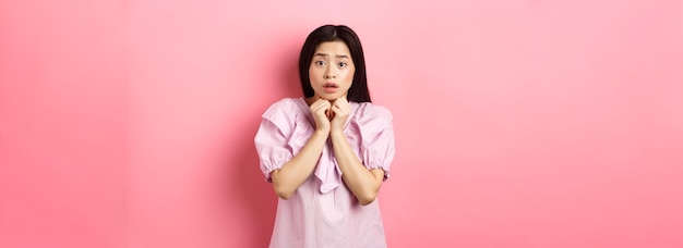 Photo gratuite fille timide effrayée regardant la caméra inquiète debout sur fond rose