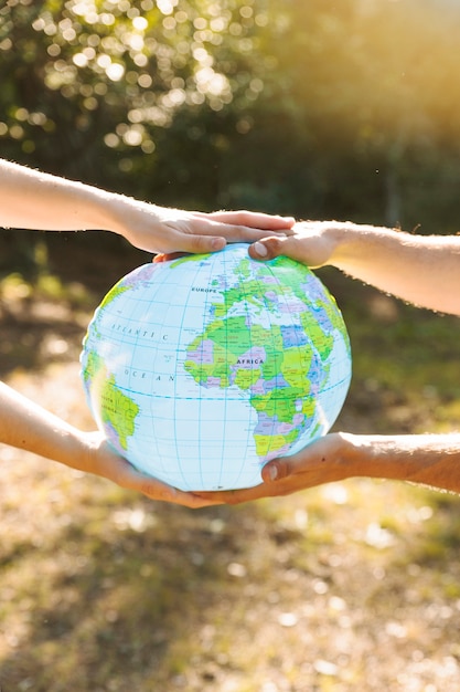 Photo gratuite globe bleu en mains avec la forêt sur fond