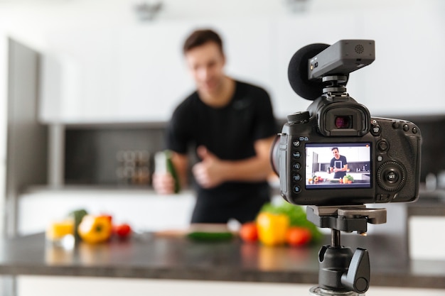 Photo gratuite gros plan d'une caméra vidéo filmant un jeune blogueur masculin souriant