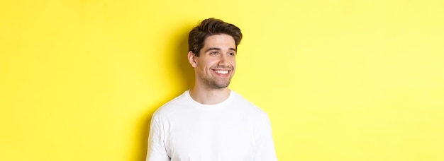 Photo gratuite gros plan d'un homme barbu attrayant en t-shirt blanc souriant regardant à gauche l'espace de copie debout contre