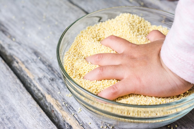 Gros plan de la main d'un bébé mis dans un bol de grains amarath entiers frais